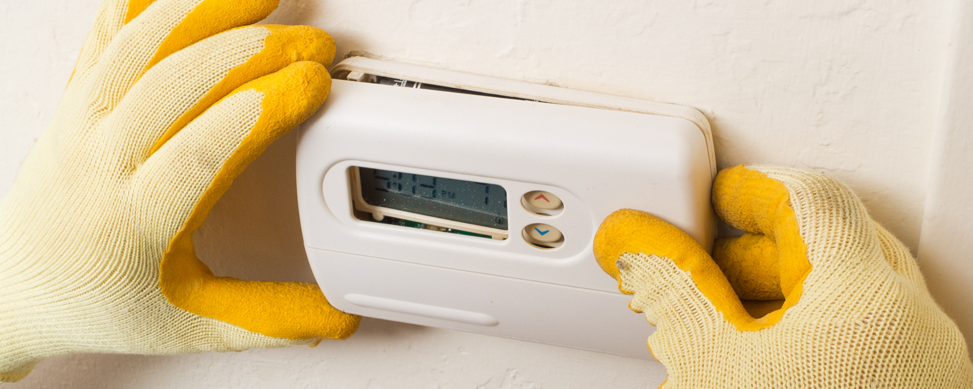 HVAC technician repairing a residential HVAC thermostat 